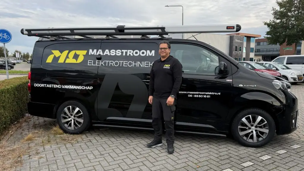 Bedrijfsbus Maasstroom Elektrotechniek met bedrijfsreclame. Een volledig elektrische Toyota Proace. Jayant staat ernaast.